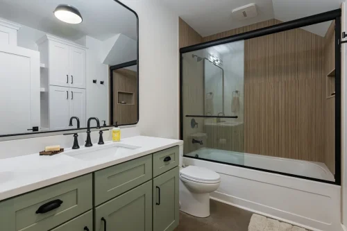 Bathroom with wood panel shower and green vanity.