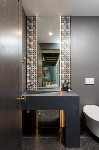 Stylish powder room with colorful geometric tile accents and concrete vanity.