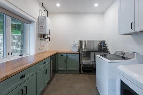 Laundry room with green cabinets, wood countertop, and washer dryer.