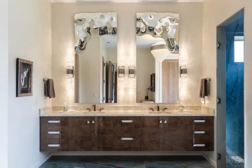 Bathroom with a floating double vanity, stone countertop, tall decorative mirrors, and contemporary wall sconces.