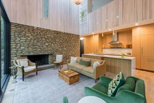 Modern living room with stone fireplace and open kitchen.