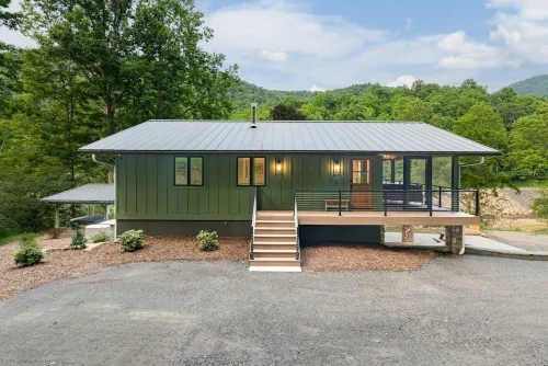 Green mountain home with metal roof and front steps.