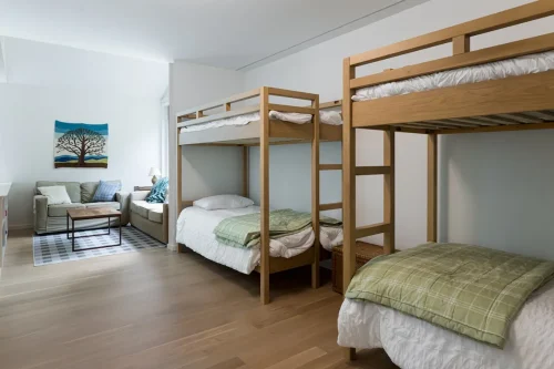 Bunk room with four wooden beds and small sitting area.