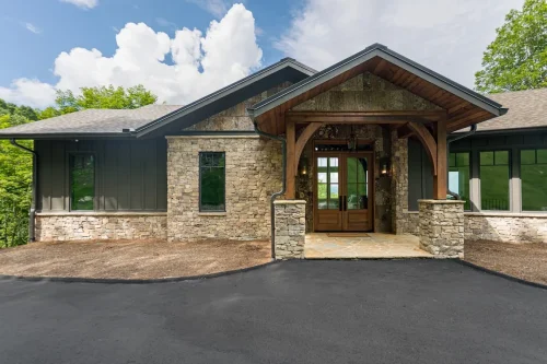 Exterior front view of mountain home with stone facade, wood beams, and covered entry.