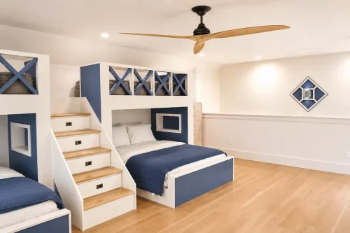 Bunk room with built-in blue and white beds, storage stairs, hardwood floors, and a wood ceiling fan