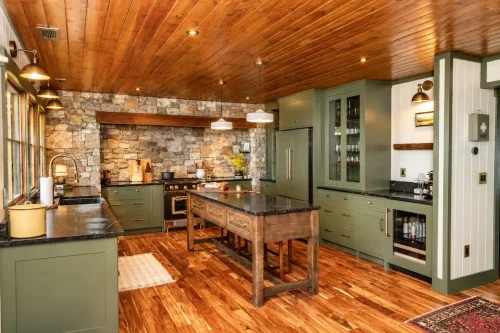 Kitchen with green cabinetry, stone backsplash, wood-paneled ceiling, hardwood floors, and a rustic wood island.