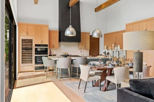 Bright kitchen featuring custom wood cabinets, oversized island, sleek black range hood, and built-in wine fridge