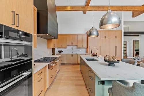 Spacious kitchen with Miele appliances, marble counters, pendant lighting, and open flow to dining and living areas.