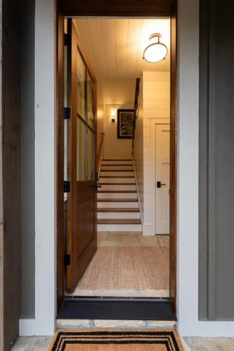 Entryway with a wood front door, shiplap walls, stone flooring, and staircase with wood treads.