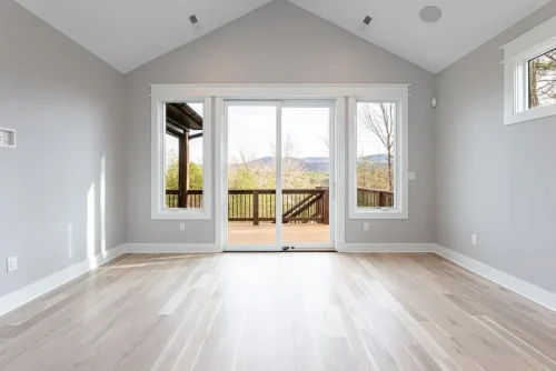 Open living area with vaulted ceiling, hardwood floors, and sliding glass doors opening to a mountain-view deck.