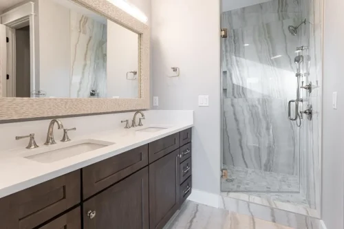 Bathroom with a double vanity, dark wood cabinetry, and glass-enclosed tile shower.