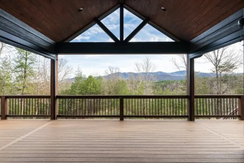 Covered deck with vaulted wood ceiling, exposed beams, and expansive mountain views.