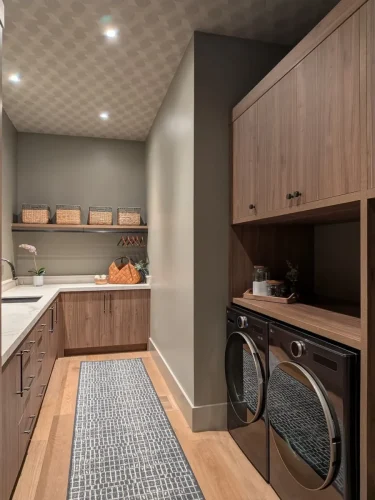 Primary bathroom with a freestanding tub, marble-look flooring, dark tiled accent wall, wood cabinetry, and statement chandelier.