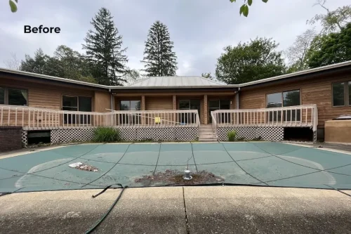Before renovation view of the backyard pool, wood-sided exterior, and raised deck.