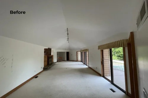 Before renovation living room with carpet, brick fireplace, wood trim, and sliding glass doors.
