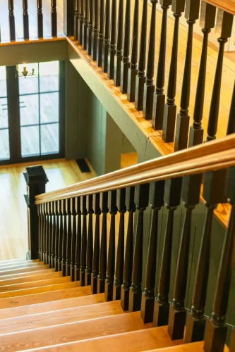 Wood staircase with dark turned balusters and handrails overlooking the entry below.
