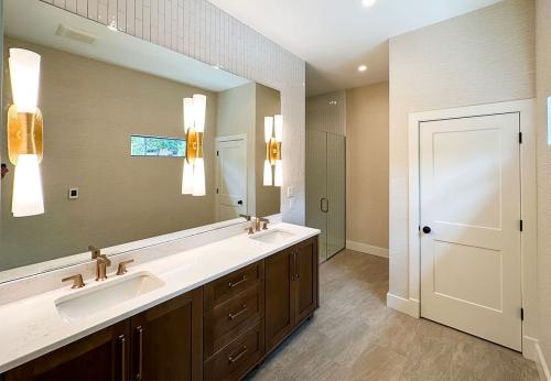 Inside of the Tulip Poplar home; WNC Parade of Homes; Modern Home view of primary bathroom; double vanity; toilet closet; curbless shower; modern light fixtures in mirror.