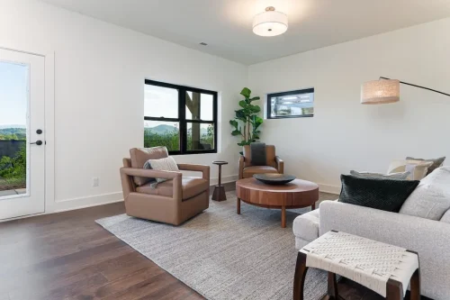 Sitting room with wood flooring, neutral furnishings, black-framed windows, and mountain views.