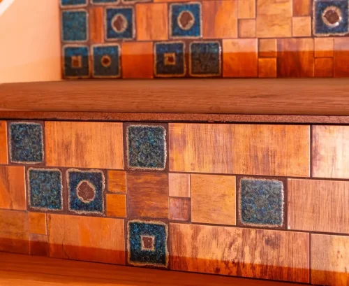 Close-up of custom wood cabinetry accented with blue-green decorative tiles.