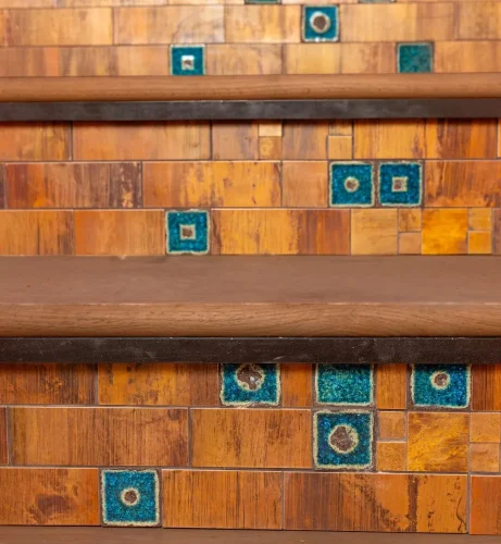 Close-up of custom wood cabinetry with geometric woodwork and blue-green tile accents.