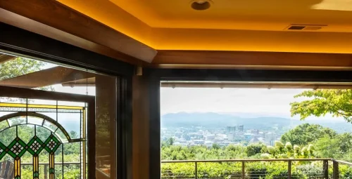 Mountain and city views framed by large windows and a decorative stained-glass panel.