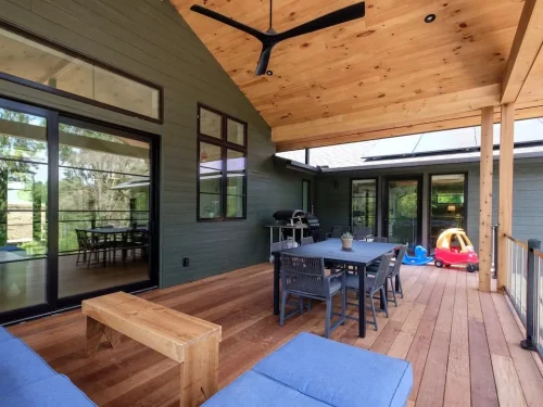 Spacious covered deck with wood ceiling and flooring, outdoor dining area, and seating.