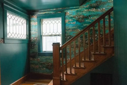 Staircase with teal walls and leaded glass windows.