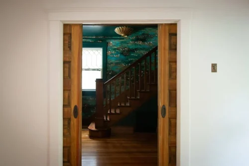 Wooden staircase seen through sliding doors with teal walls.