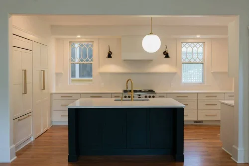 White kitchen with black island and brass fixtures.