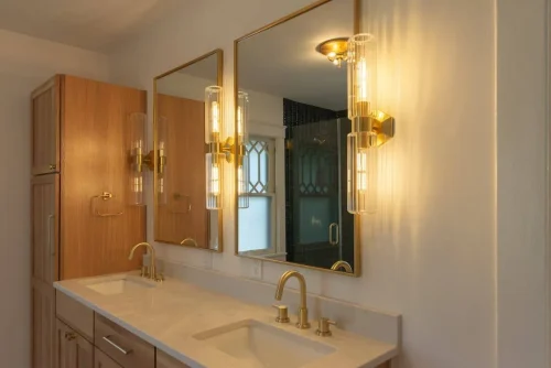 Double vanity with gold fixtures and light wood cabinetry.