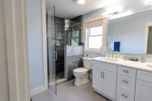 Modern bathroom with glass shower and gray tile.
