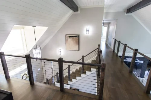 Upstairs hallway with wood floors and cable railing.