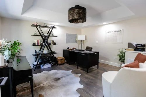 Home office with dark furniture and X-shaped bookshelf.