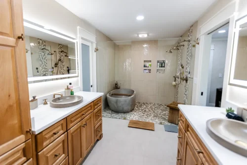 Spacious bathroom with wood vanities and stone soaking tub.
