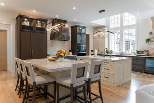 Kitchen with two white islands, one with sink and one with chairs.