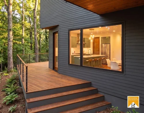 1. deck.jpg: Wood deck with steps and metal railing beside a dark-sided home, with a large kitchen window and surrounding trees.