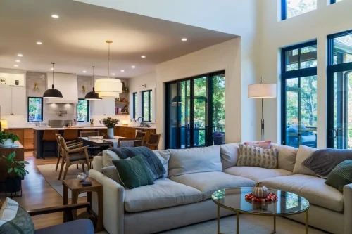 Open-concept living, dining, and kitchen area with large black-framed windows and abundant natural light.