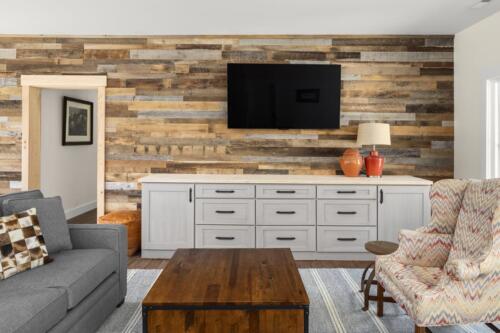 Den with wood wall, white cabinet, TV and furniture.
