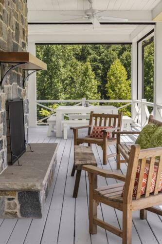 Outdoor fireplace with two wooden chairs on deck.