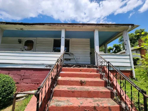 Worn house exterior with peeling paint and crumbling front steps.