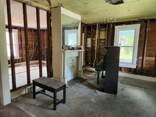 Gutted living room with exposed studs and damaged ceiling.