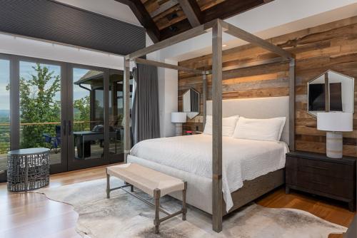 Rustic Mountain Estate bedroom with wood plank wall, sliding glass door onto patio and wood framed bed.