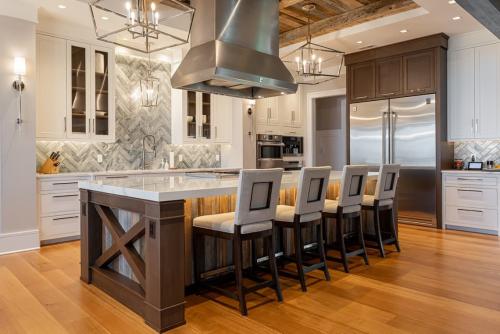 Rustic Mountain Estate kitchen with large island containing stove and hood and 4 chairs/stools.