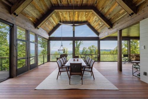 Rustic Mountain Estate large screened-in back porch with long dining table and chairs.