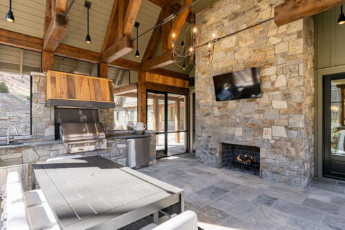 Secluded Sanctuary porch with stone fireplace, kitchen and seating area.