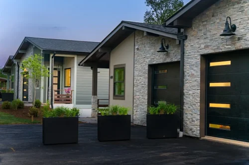 Row of contemporary homes featuring stone accents, covered entries, and black garage doors.