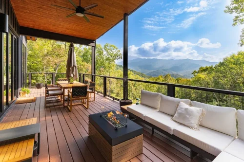Outdoor living deck with lounge seating, dining table, ceiling fan, and fire table, showcasing sweeping views of the Blue Ridge Mountains.