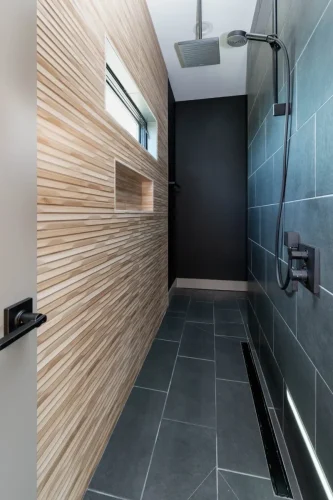 Walk-in shower with textured wood-look tile wall, dark floor tile, and rainfall showerhead.
