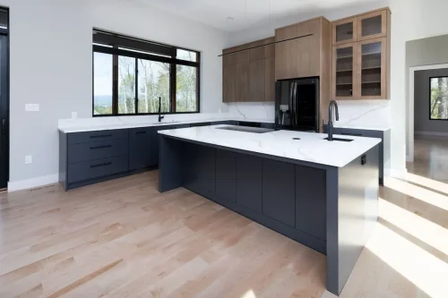 Open kitchen with sleek two-tone cabinetry, white quartz counters, and a large island with modern fixtures.