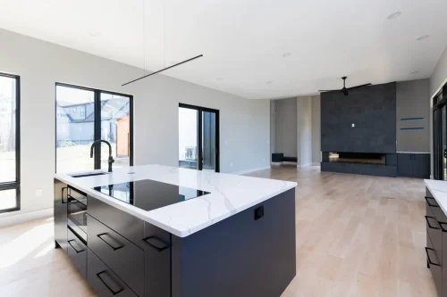 Bright open floor plan with kitchen island overlooking a spacious living area featuring a tiled fireplace and sliding glass doors.